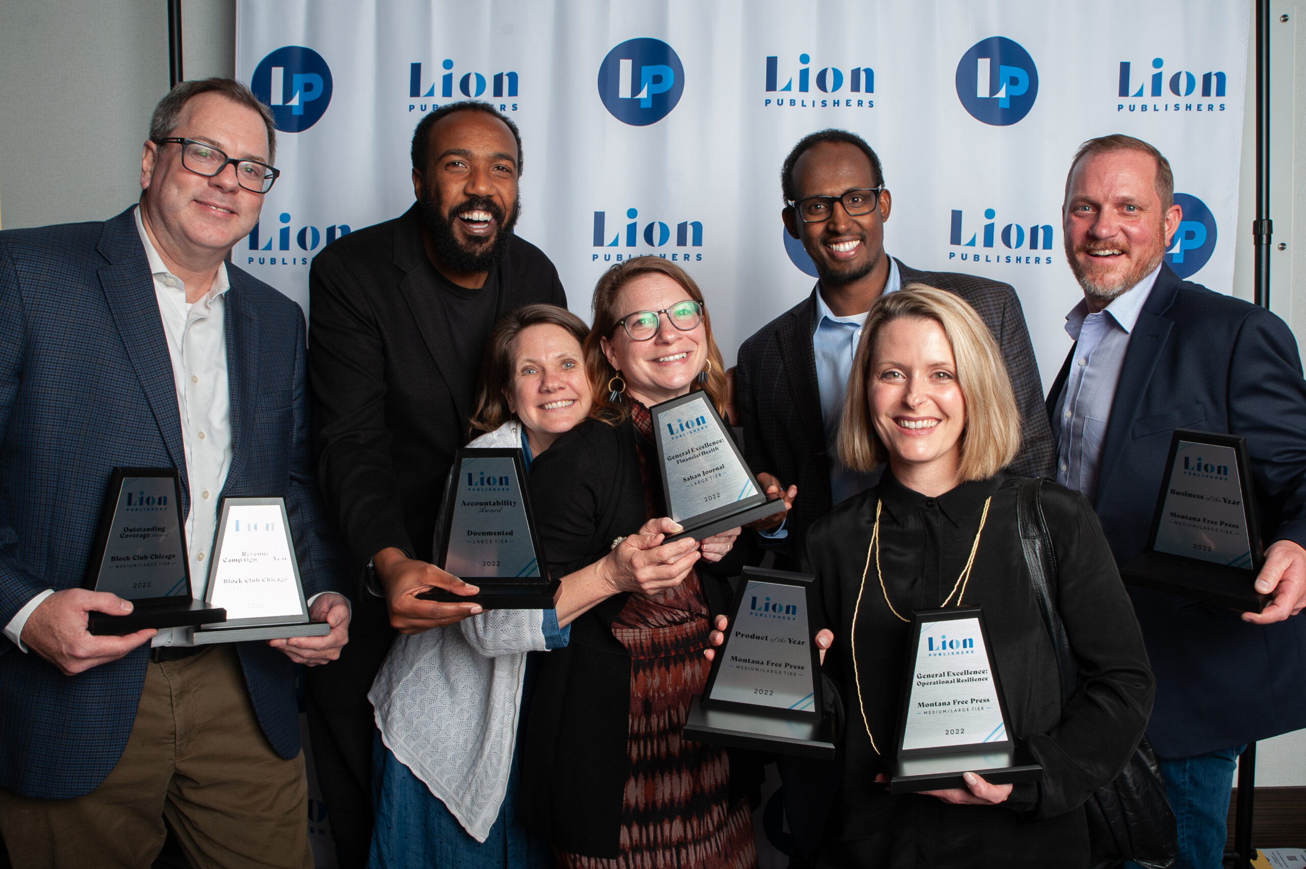 Happy group of award winners holding their awards and smiling